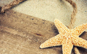 A Vibrant Yellow Starfish Resting On Wooden Surface Wallpaper