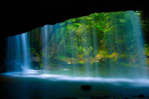 A Waterfall Is Flowing Through A Cave Wallpaper