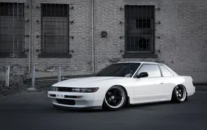 A White Car Parked In Front Of A Building Wallpaper