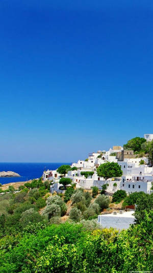 A White Village With Trees And A Blue Sky Wallpaper