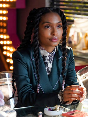 A Woman In A Green Suit Sitting At A Table Wallpaper