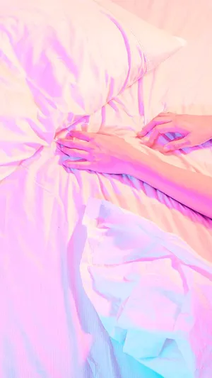 A Woman Laying On A Bed With A Pink Blanket Wallpaper