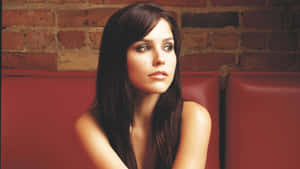 A Woman Sitting On A Red Couch With Long Hair Wallpaper