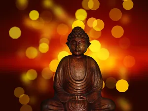 A Wooden Buddha Statue Surrounded By An Ethereal Setting. Wallpaper