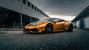 A Yellow Sports Car Parked In Front Of A Building Wallpaper