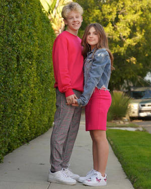 A Young Couple Standing On A Sidewalk Wallpaper