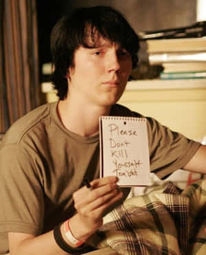 A Young Man Holding A Note In Bed Wallpaper