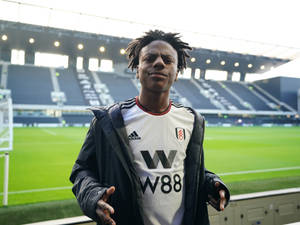 A Young Man Standing In Front Of A Stadium Wallpaper