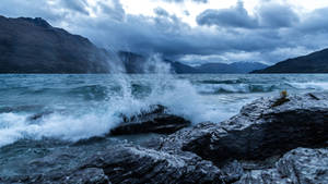 Aesthetic Fury Of Ocean Waves Crashing Over Rocky Coastline Wallpaper