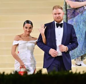 Alexandria Ocasio-cortez Locking Arms With Riley Roberts Wallpaper