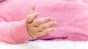 An Adorable Baby Hand In A Pink Onesie Wallpaper