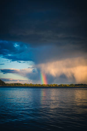 An Idyllic River View With A Beautiful Rainbow Arching Over It Wallpaper