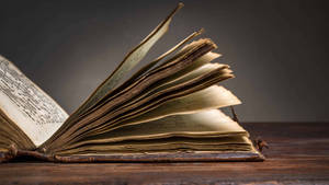 An Open Book On A Wooden Table Wallpaper