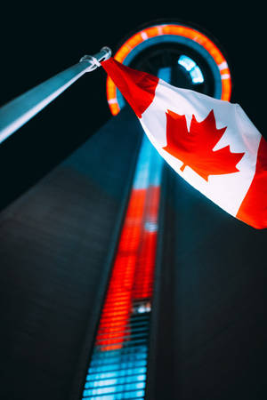 Beautiful View Of The Cn Tower With Canadian Flag Waving Proudly Wallpaper