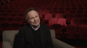 Billy Crystal During An Interview In An Ornate Movie Theatre Wallpaper