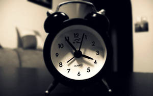 Black Alarm Clock On Desk Wallpaper