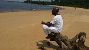 Black Cameroon Man Sitting On A Branch Of Tree Wallpaper