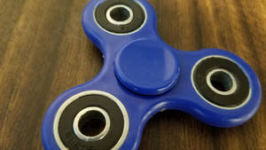 Blue Fidget Toy On Wood Wallpaper