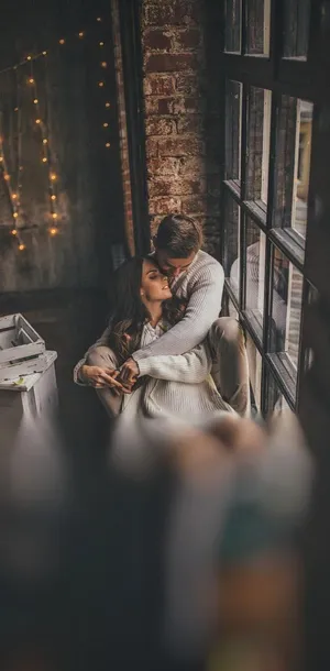 Boyfriend And Girlfriend Cuddling By The Window Wallpaper