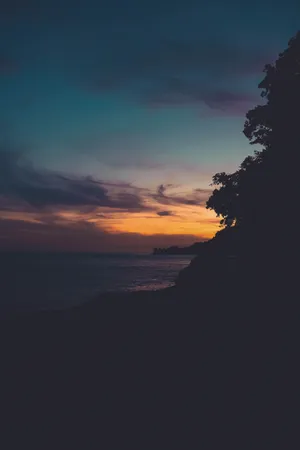 Bright Shades Of Red And Orange Glow Over A Peaceful Landscape During Sunset Wallpaper