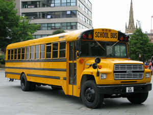 Bright Yellow School Bus Parked In A Campus Wallpaper