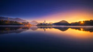 Caption: Breathtaking Sunset Over Lake Bled Panorama Wallpaper