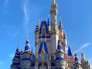 Caption: Glistening Disney Castle Under A Bright, Sunny Sky. Wallpaper