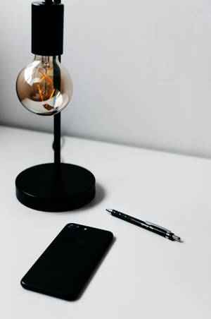 Caption: Illuminated Iphone On A Minimalist Desk Wallpaper