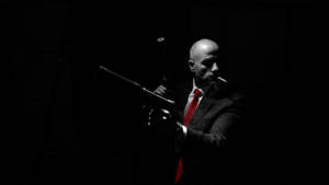 Caption: Mysterious Real Hitman In Dark Backdrop Wallpaper