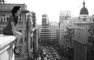 Caption: Reflective White Lady Overlooking The City From A Rooftop Wallpaper