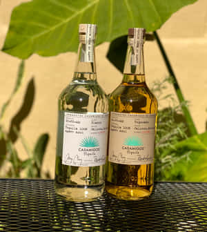 Casamigos Tequila Blanco And Reposado Liquor Bottles On Mesh Table Wallpaper