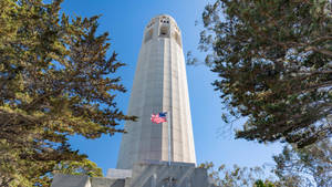 Coit Tower With A Proudly Waving American Flag Wallpaper