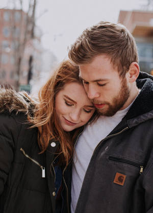 Couple Hugging In Black Coats Wallpaper