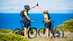 Couple Mountain Biking At Mountain Lake Wallpaper