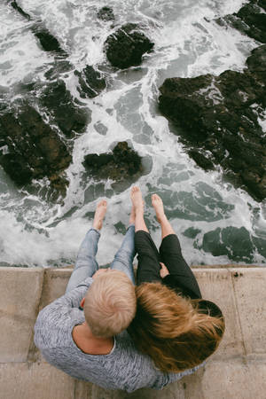 Couple Sitting Near The Sea Wallpaper