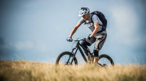 Cyclist Mountain Biking At Mountain Field Wallpaper