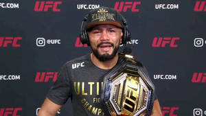 Deiveson Figueiredo Wearing Headset While Holding Championship Belt. Wallpaper