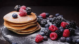 Delicious Pancakes Topped With Sugar And Berries Wallpaper