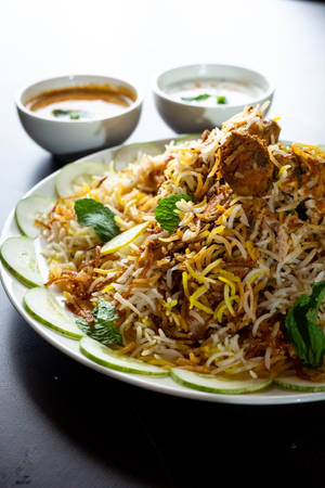 Delightful Chicken Biryani Garnished With Fresh Cucumbers Wallpaper