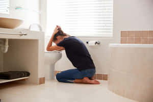 Distressed Woman Experiencing Nausea In The Bathroom Wallpaper