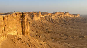 Dusk Falling Over The Majestic Jebel Fihrayn Cliffs In Saudi Arabia Wallpaper