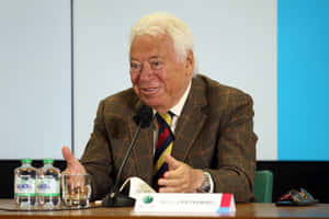 Elderly Gentleman Speakingat Event Wallpaper