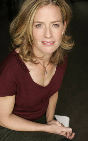 Elisabeth Shue Wearing Maroon Top With Both Hands On Lap Smiling Wallpaper