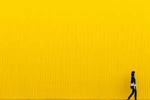 Embracing Boldness - Girl Against Yellow Wall Wallpaper