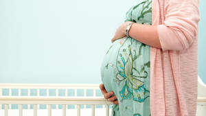 Embracing Motherhood - A Pregnant Woman Gently Holding Her Belly Wallpaper