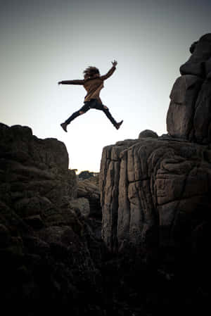 Energetic Leap On A Rocky Cliff Wallpaper