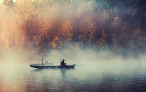 Enjoying An Early Morning Fishing Trip In A Misty Lake Wallpaper