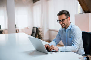 Entrepreneur Smiling While Working On Laptop Wallpaper