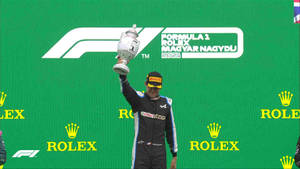 Esteban Ocon Raising Trophy In Victory Wallpaper