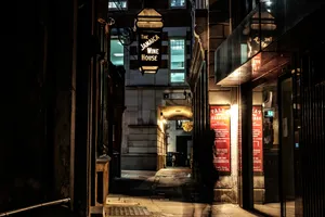 Experience The Hustle And Bustle Of City Life In This Street Alley At Night. Wallpaper